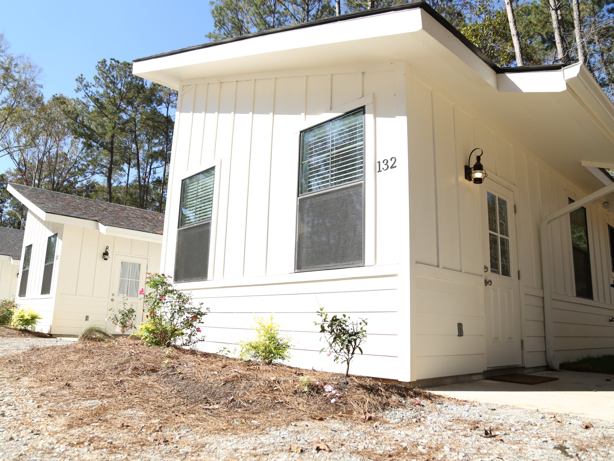 Modern white cabin with a covered porch among pine trees at Fireside RV Resort
