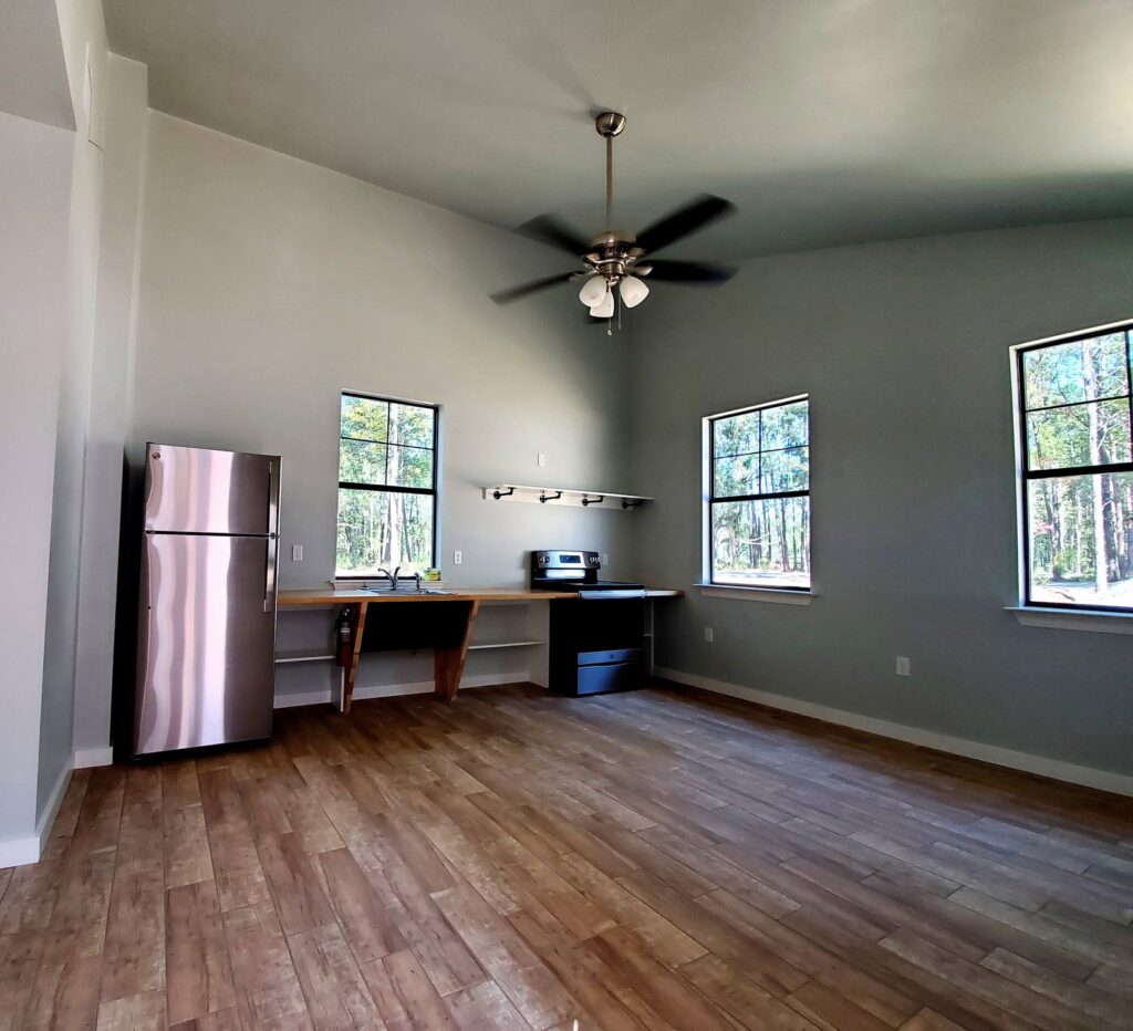 A bright, empty kitchen and living area with light gray walls and wood-look flooring at Fireside RV Resort in Ponchatoula, Louisiana.