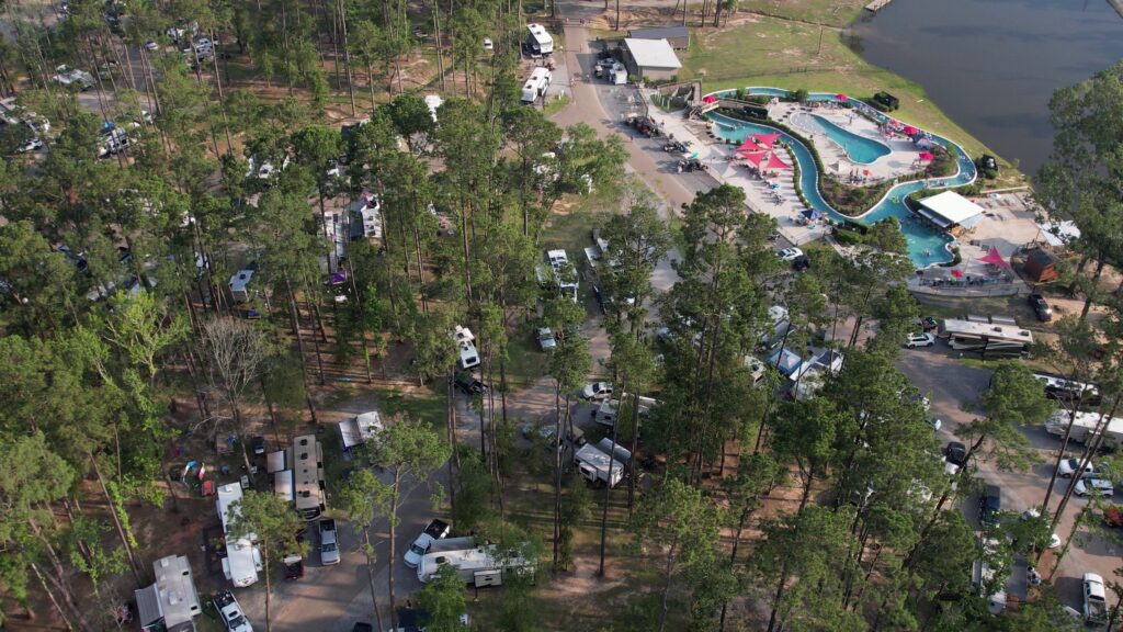 Aerial view of Fireside RV Resort grounds and lake surrounded by pine trees in Ponchatoula, Louisiana